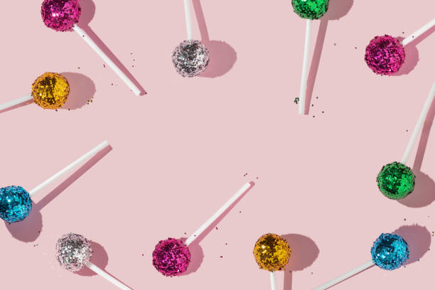 istock Creative colorful pattern or frame with lollipops and bright pink,yellow,green,blue and silver glitter on pastel pink background. Party fun sweet life idea with lollipop or candy. Minimal flat lay. 1370700329
