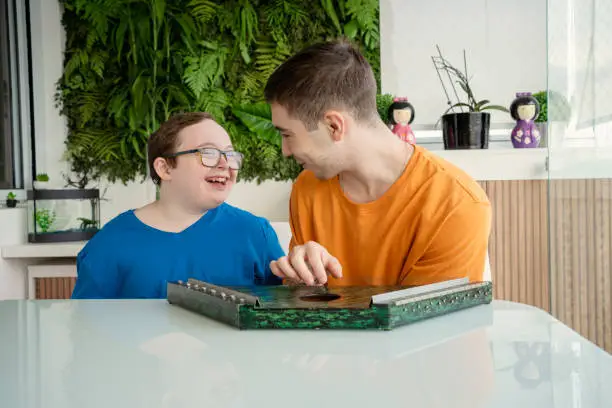 Photo of Boy with down syndrome and his brother learning music. Playing harp and harmonica.