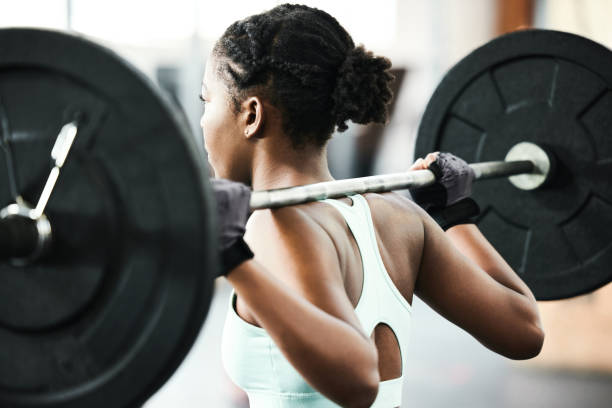 aufnahme einer nicht erkennbaren frau, die während ihres trainings im fitnessstudio eine langhantel benutzt - krafttraining stock-fotos und bilder