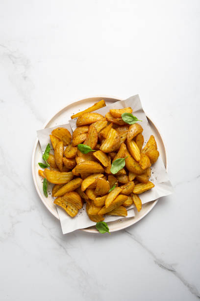 Golden roasted potatoes wedges on plate from above food stock photo