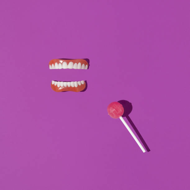 istock Creative layout with false teeth and lollipop on bright purple background. 80s or 90s retro aesthetic concept. Surreal idea with lollipop 1370701636