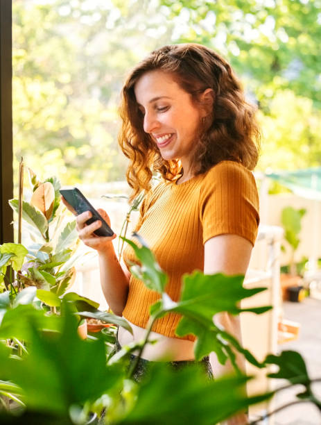 istock Beautiful young woman using her mobile phone at home 1370703407