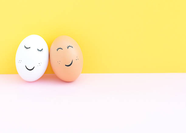 istock Easter concept. Two creative white and brown eggs with painted eyes and a mouth on a yellow-pink background. Free place. 1370704764