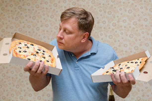 istock A fat man bought two boxes of pizza and sniffs them with pleasure 1370706116