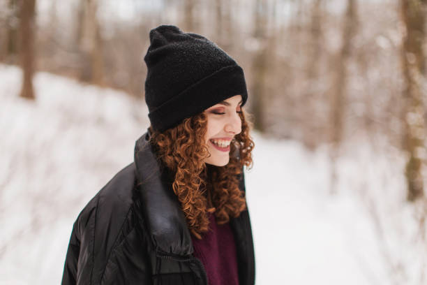 Redhead curly beautiful girl in jacket and hat in forest. Portrait with smile. Winter break. Woman enjoying vacation. Visit local attractions. Girl laughing in nature. Feel happiness. Walking tour Redhead curly beautiful girl in jacket and hat in forest. Portrait with smile. Winter break. Woman enjoying vacation. Visit local attractions. Girl laughing in nature. Feel happiness. Walking tour irish travellers photos stock pictures, royalty-free photos & images