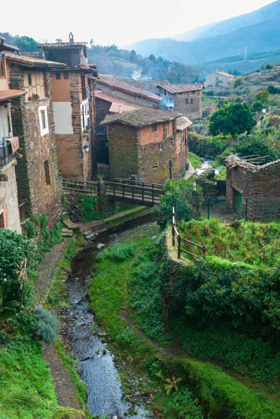 istock Arrago River by Robledillo de Gata with popular stone, adobe and slate architecture with a wooden bridge. Vertical 1370709340