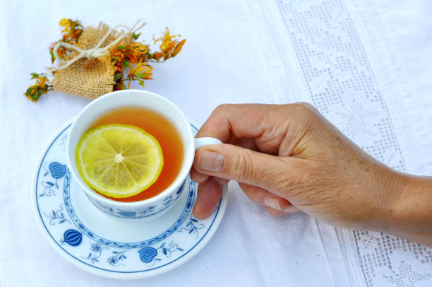 femme tenant la main du biscuit buvant une tisane chaude - five oclock tea photos et images de collection