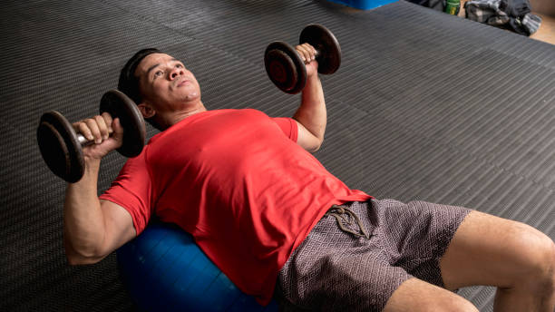 istock A fit and handsome asian guy does Stability Ball Dumbbell Chest 1370709974