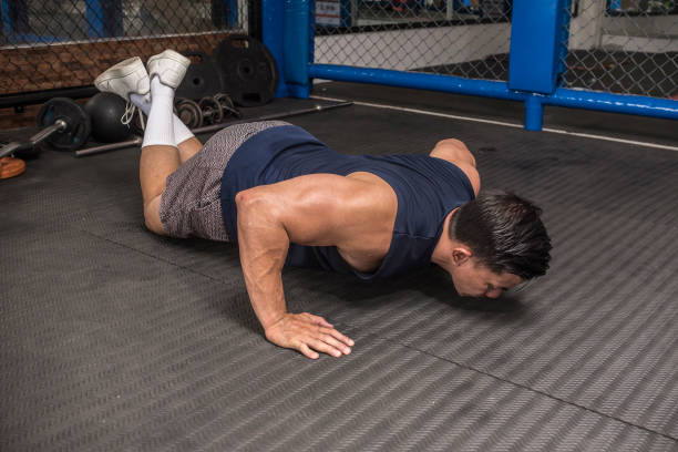istock An athletic man does wide stance half push ups on the rubber matted floor. Also known as knee pushups. HIIT or calisthenics workout at an MMA gym. 1370709987