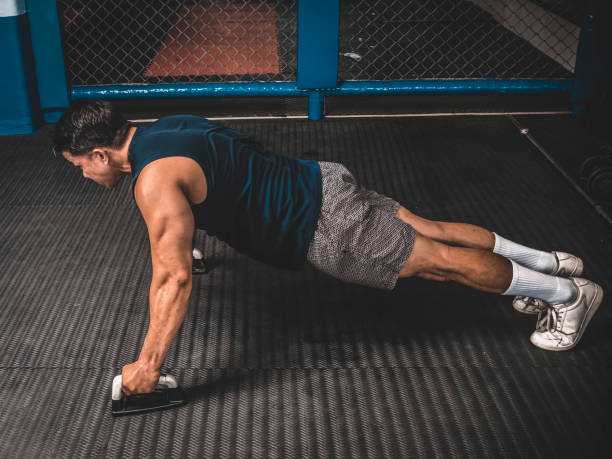 istock An athletic man does pushups with push-up handle bars on the rubber matted floor. HIIT or calisthenics workout at an MMA gym. 1370709991