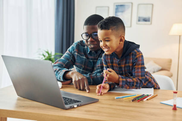 istock With laptop on table. African american father with his young son at home 1370710574