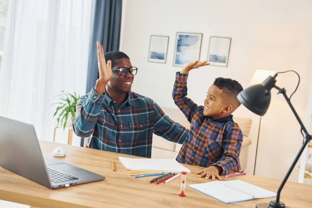 istock Using laptop. African american father with his young son at home 1370710679