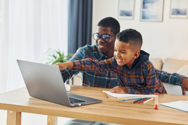 istock Using laptop. African american father with his young son at home 1370710699