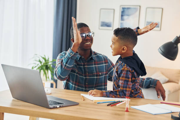 istock Using laptop. African american father with his young son at home 1370710703