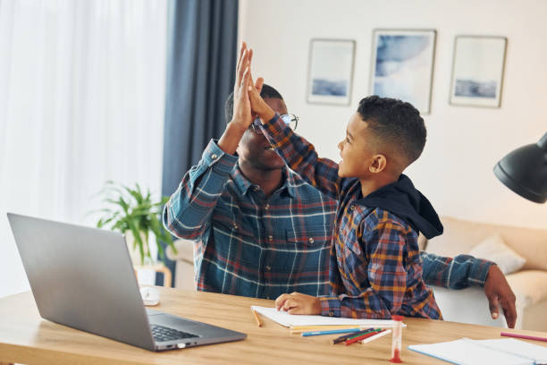 istock Using laptop. African american father with his young son at home 1370710708