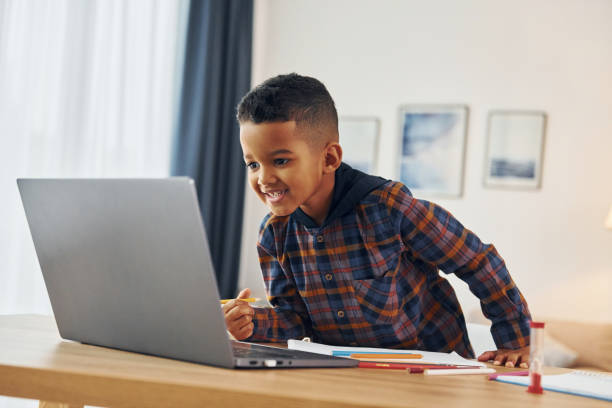 istock With laptop. Cheerful young boy is at home alone 1370711273