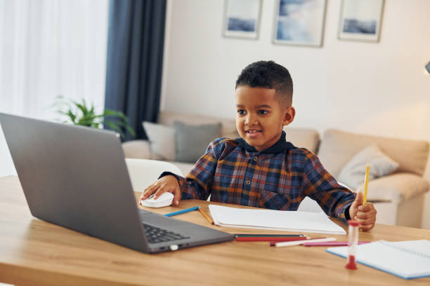 istock With laptop. Cheerful young boy is at home alone 1370711303