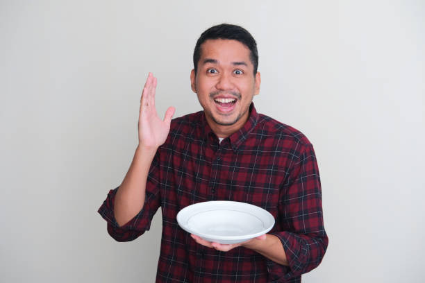istock Adult Asian man showing excited expression while holding empty dinner plate 1370711511