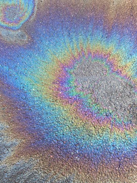 imagen de combustible y agua de automóvil derramados en la superficie de una carretera asfaltada, efecto arco iris creado por la mancha de aceite de gasolina en el asfalto, vista elevada - pollution oil oil slick water pollution fotografías e imágenes de stock