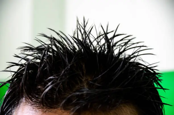 Photo of Spike hair style of a young man. Closeup of a spiky hairstyle of student using hard hair gel in the class.