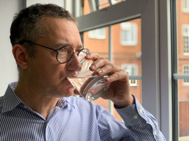 istock Middle aged man is standing by the window and drinking water 1370712771