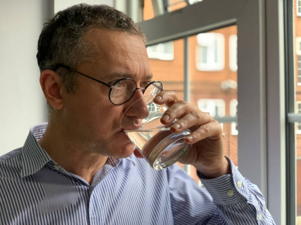 istock Middle aged man is standing by the window and drinking water 1370712781