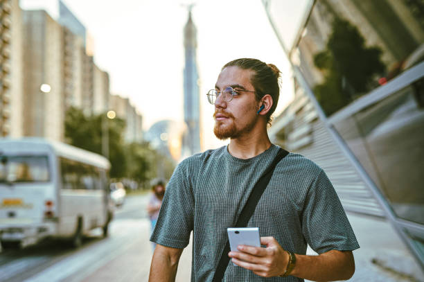 istock Shot of a handsome young man standing alone and looking contemplative while using his cellphone in the city 1370713307