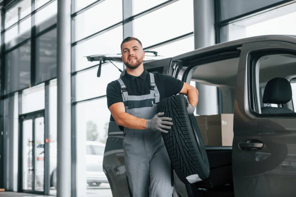 istock With tire in hands. Man in uniform is working in the autosalon at daytime 1370713541