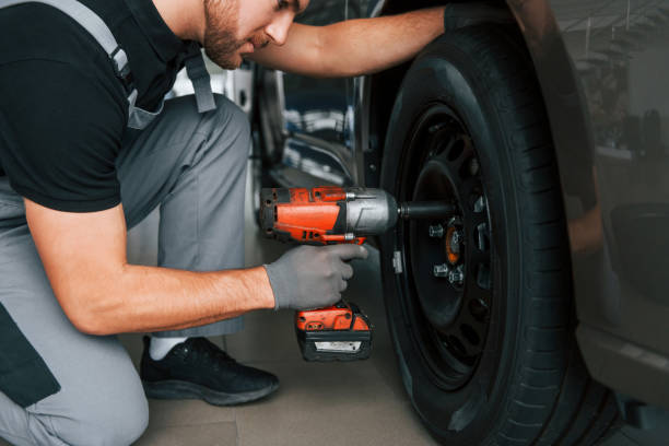 istock Changing of the tires. Man in uniform is working in the autosalon at daytime 1370713708