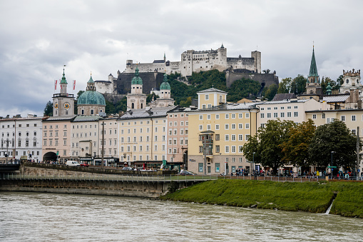 Salzburg, Austria, 28 August 2021: old medieval castle on hill, Hohensalzburg Fortress, embankment panorama of river Salzach, renaissance and baroque houses, Facade of stone building at summer day