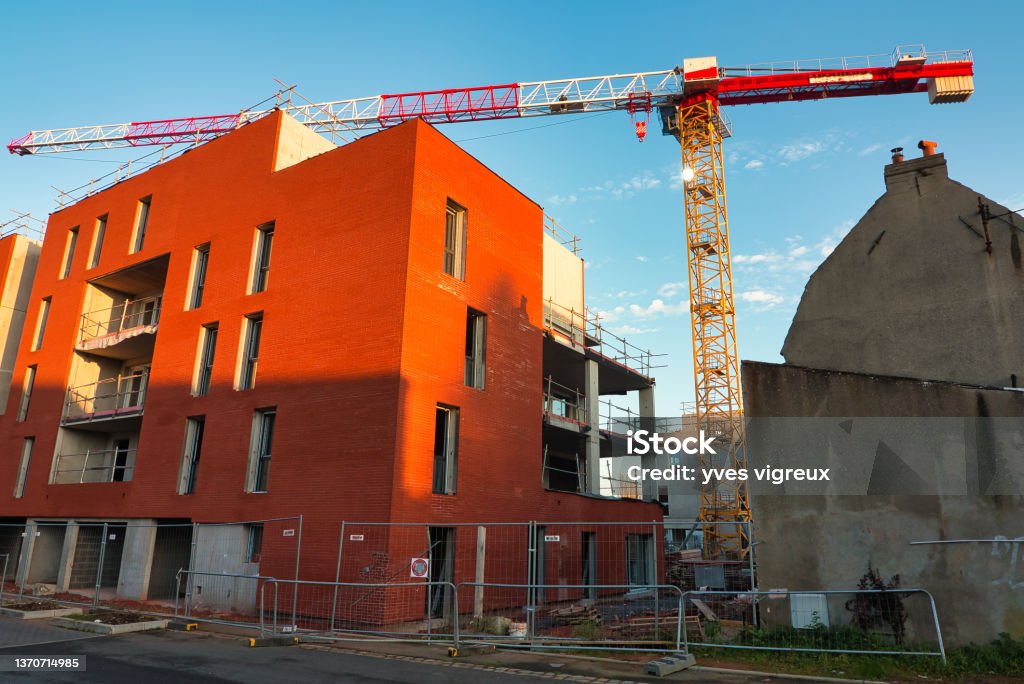 a crane on a construction site a red crane on a construction site of a building and blue sky Construction Site Stock Photo