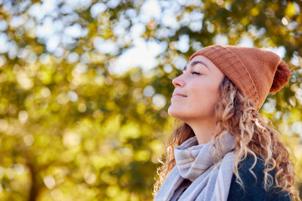 Calm Young Woman Wearing Hat And Scarf Relaxing And Breathing In Deeply In Autumn Park stock photo