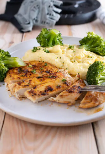 Healthy and gluten free fitness meal for dinner or lunch with homemade pan fried chicken breast, low fat polenta and broccoli. Served on a plate. Ready to eat.