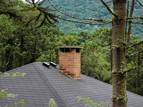 Brick chimney in a grey roof. Green background