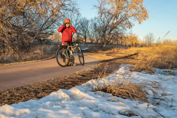 senior male cyclist with his touring bike on a biking trail along Poudre River in Fort Collins, Colorado, sunset winter scenery