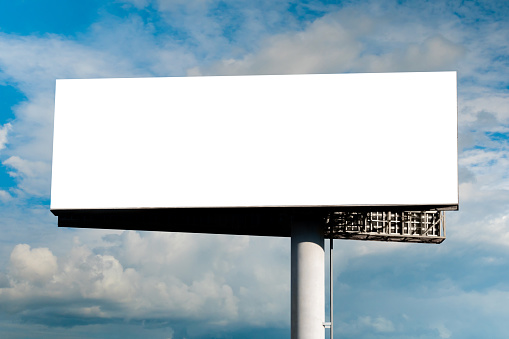 Blank wide large display or white billboard against blue sky with white clouds - mock up. Template, consumerism, advertising, white screen, copy space and mockup concept
