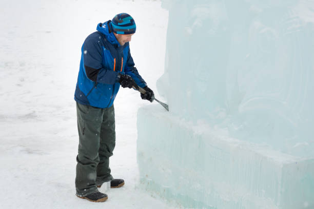 istock Sculptor in a blue winter suit with a chisel in his hands at work 1370723286