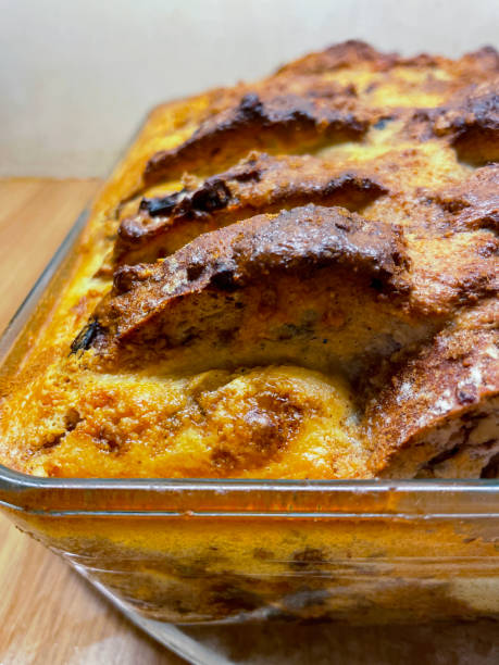 immagine di una pirofila di vetro contenente ingredienti cotti per un budino di pane e burro a strati, fette di strati di pane bianco imburrato cosparsi di frutta secca e mele rosse e verdi a cubetti, concentrati sul primo piano - apple and currant bread foto e immagini stock