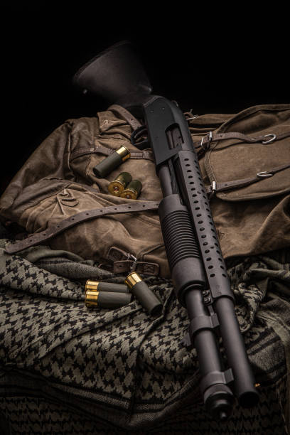 istock A black 12-gauge pump-action shotgun and ammo are on a canvas backpack. A smooth-bore weapon with a plastic stock. Dark background. 1370726549