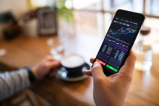 Trading with cryptocurrency on smartphone and enjoying coffee. stock photo