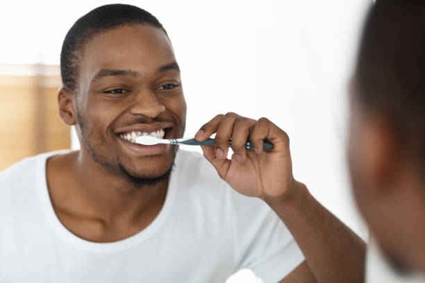 istock Morning Routine Concept. Happy Black Man Brushing Teeth Near Mirror In Bathroom 1370730222