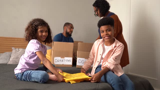 Portrait of kids sorting out clothes in boxes to donate at home