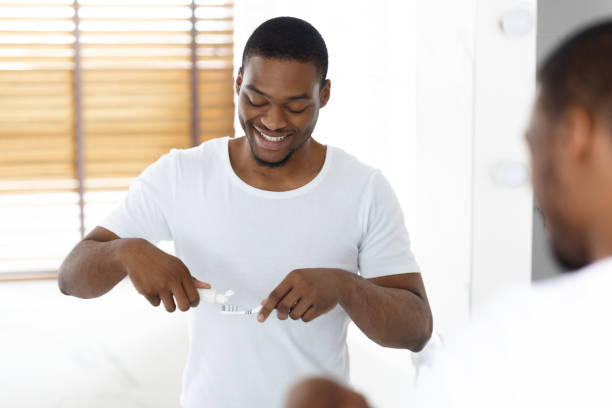 istock Handsome Black Man Applying Toothpaste On Toothbrush Near Mirror In Bathroom 1370731221