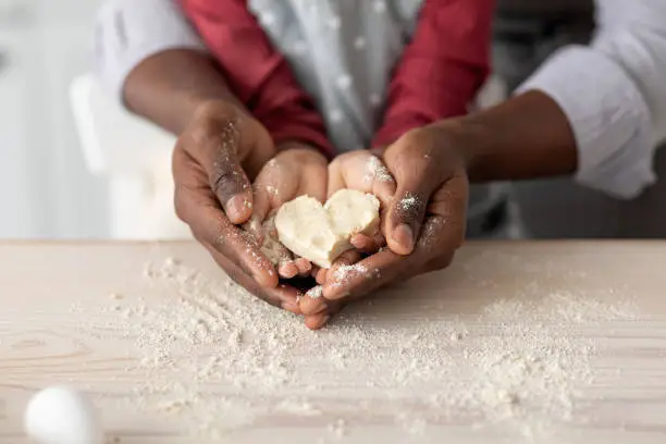 Photo of Hands of black father and daughter holding heart shaped cookies