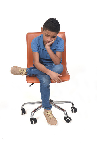 boy sitting on a chair looking at the floor on white background