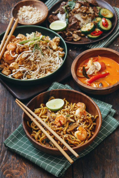 Authentic Classic Thai Dishes Authentic classic Pad Thai with shrimps. Thai fried noodle with seafood. Authentic classic Thai Tom Yum soup. Close-up composition on dark wooden background. comfort food stock pictures, royalty-free photos & images