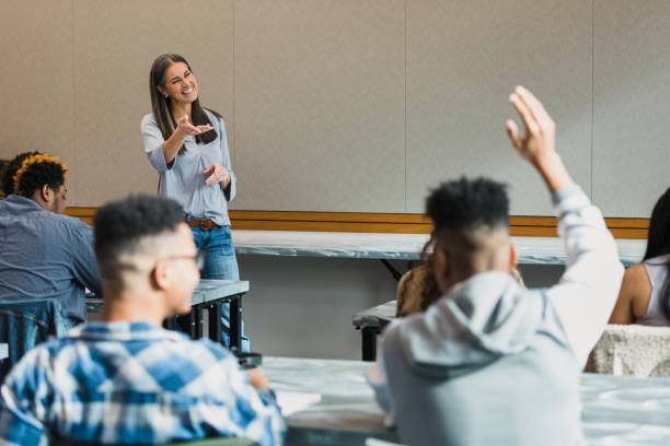 istock Teacher smiles and gestures when unrecognizable student raises hand 1370735937