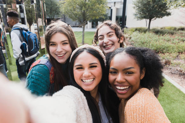 cztery nastoletnie przyjaciółki robią sobie selfie przed szkołą - mobile phone group of people photographing teenager zdjęcia i obrazy z banku zdjęć