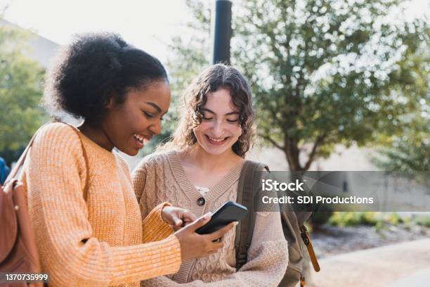 Teen Girl Shows Friend Something On Her Smart Phone Stock Photo - Download Image Now
