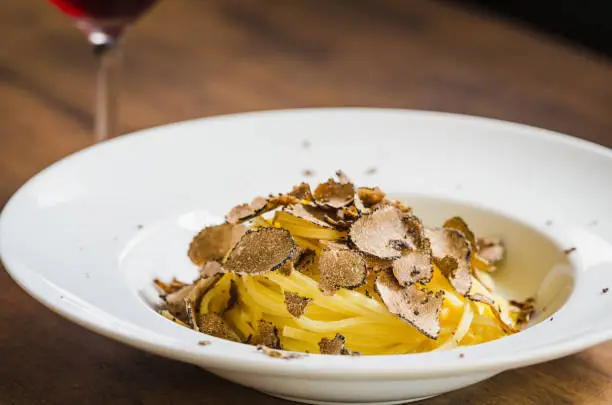 Pasta with truffles.Tagliatelle pasta plate with fresh truffle on wooden table copy space.Restaurant menu plate.